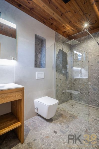 Bathroom in a recreational apartment with wooden decor and a shower with a glass partition.