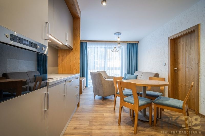 A kitchen in a holiday apartment with a wood-decor floor and a dining table.