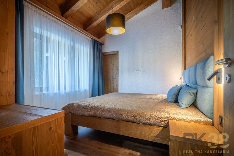 Bedroom in a holiday apartment with a wooden ceiling, bed, and floor with a wooden decor.