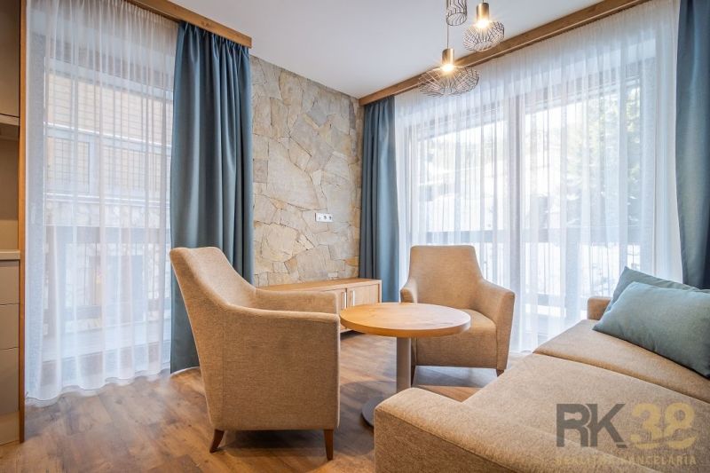 Interior of a holiday apartment with comfortable armchairs, a stone wall, and a wooden decor floor.