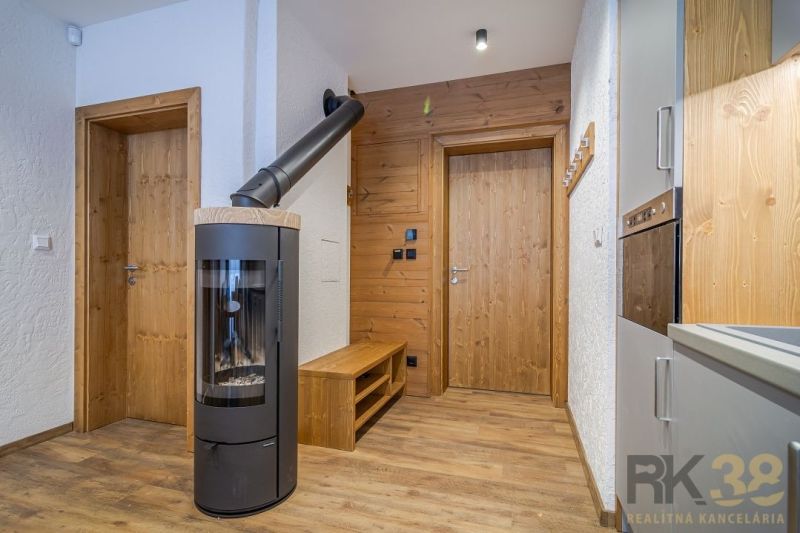 Interior of a holiday apartment with a fireplace, kitchen, and wood-decorated flooring.