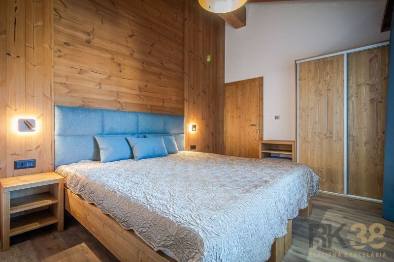 Bedroom with wood-patterned flooring in a holiday apartment. Elegant bed with upholstered headboard.