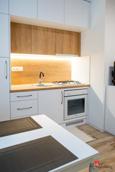 A kitchenette in a studio apartment with a wooden decor floor and comfortable lighting.
