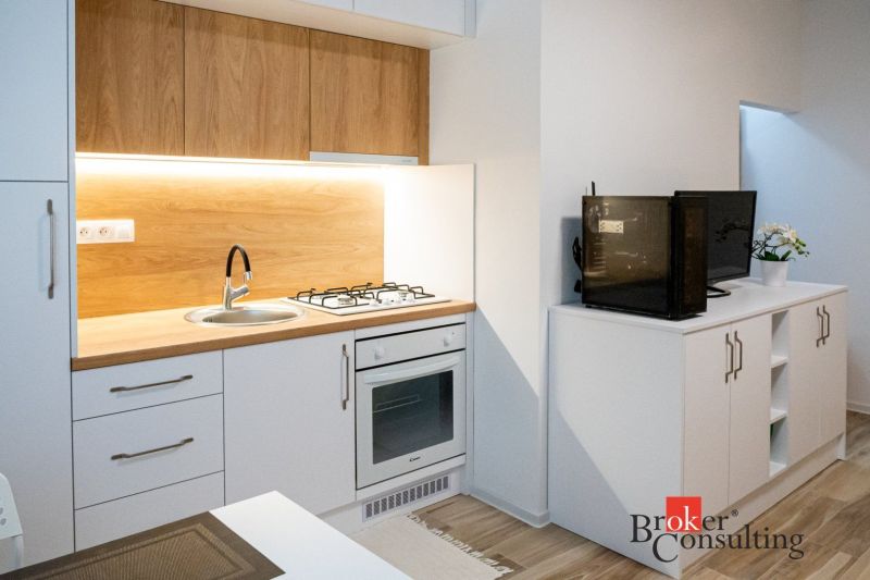 A kitchenette in a studio apartment with a wood decor and appliances.