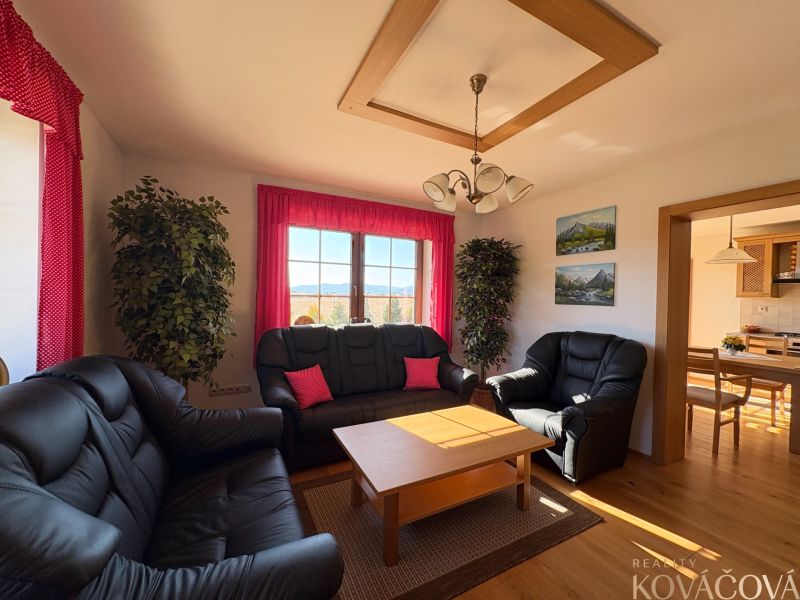 Living room with black seating, wooden table, and red curtains in a family house.