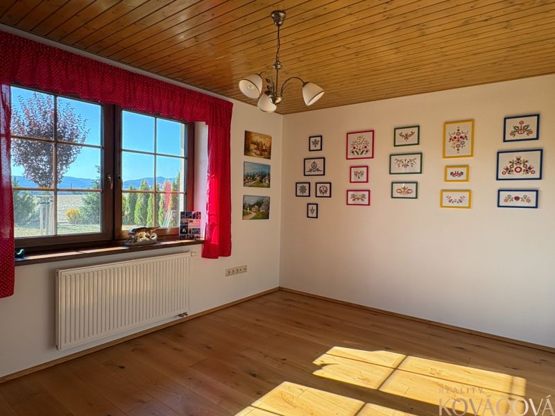 A room in a family house with a floor featuring a wooden decor, embroidered pictures on the wall.