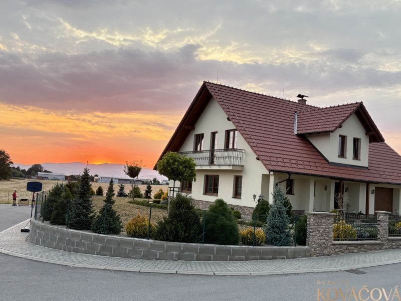 A family house in Trenčianska Turná at sunset, surrounded by a landscaped garden.