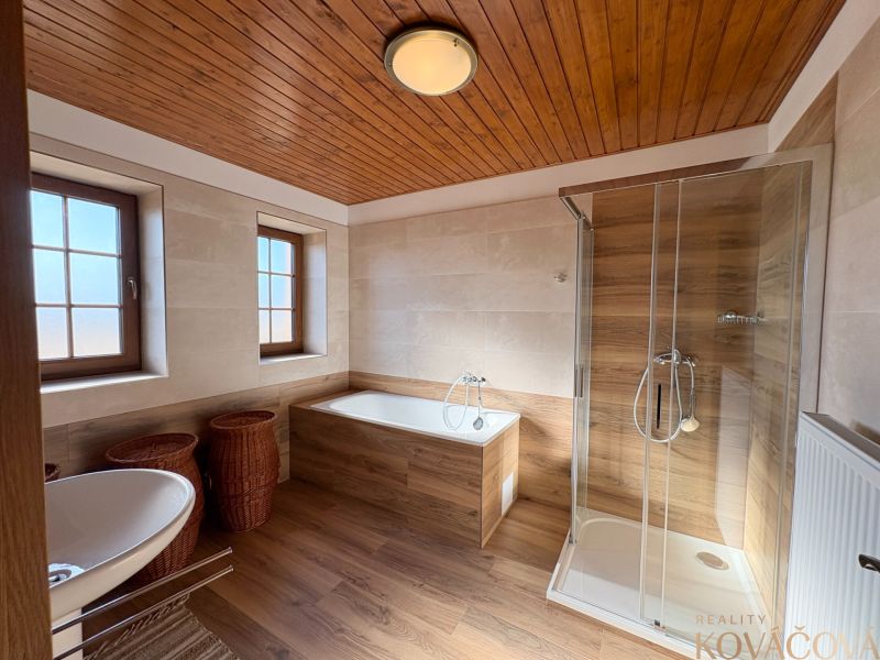 A bathroom with a bathtub, shower, and wooden decor flooring in a family house.