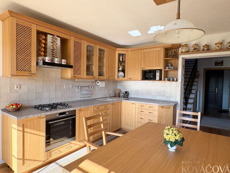 A kitchen in a family house with wooden cabinets and light walls.