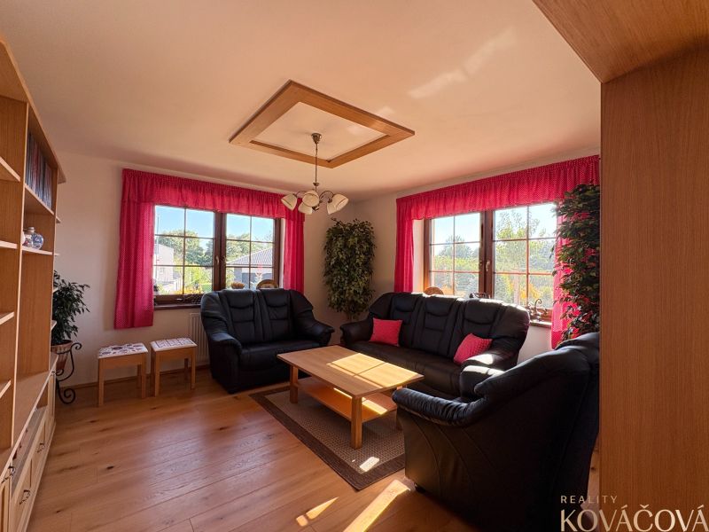 Living room in a family house with a black sofa and a wooden decor floor.