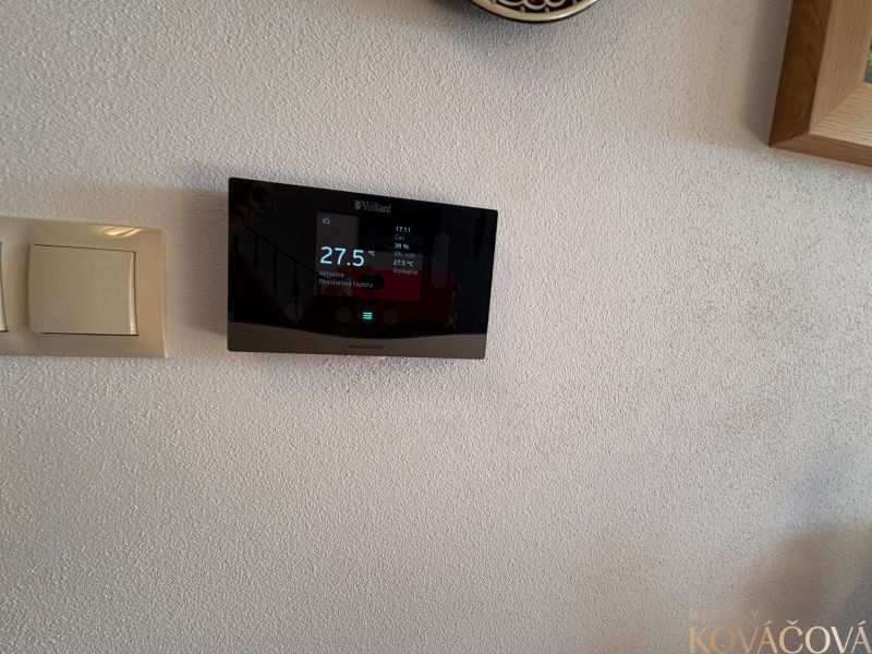Thermostat and switch on a white wall in a family house.
