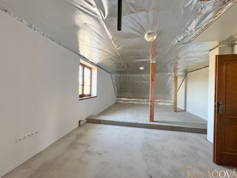Attic space with an unfinished floor, metal ceiling, and wooden columns in a family house.