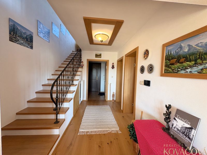 Interior of a family house with wooden decor, staircase, and artistic decorations on the wall.