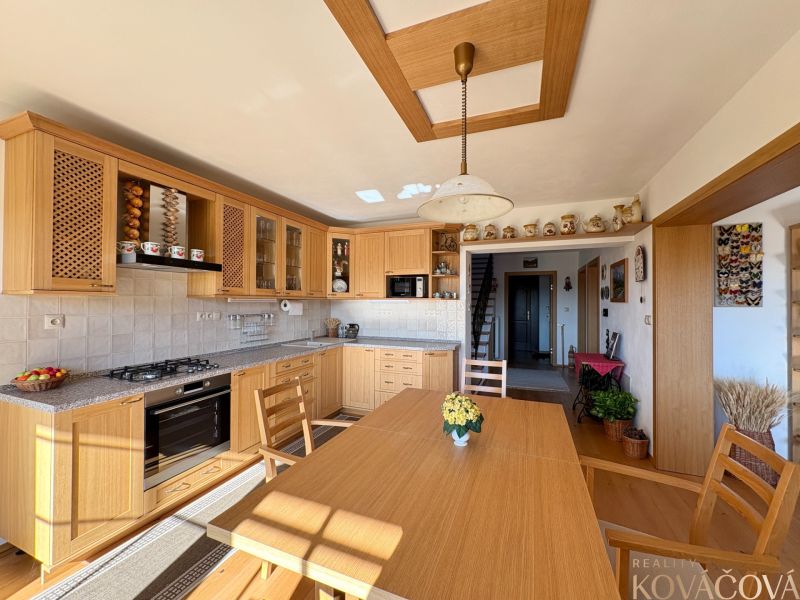 A kitchen in a family house with a wooden decor floor, light furniture, and decorations.