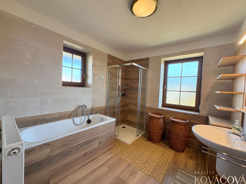 Spacious bathroom in a family house with a wooden decor floor and a bathtub.