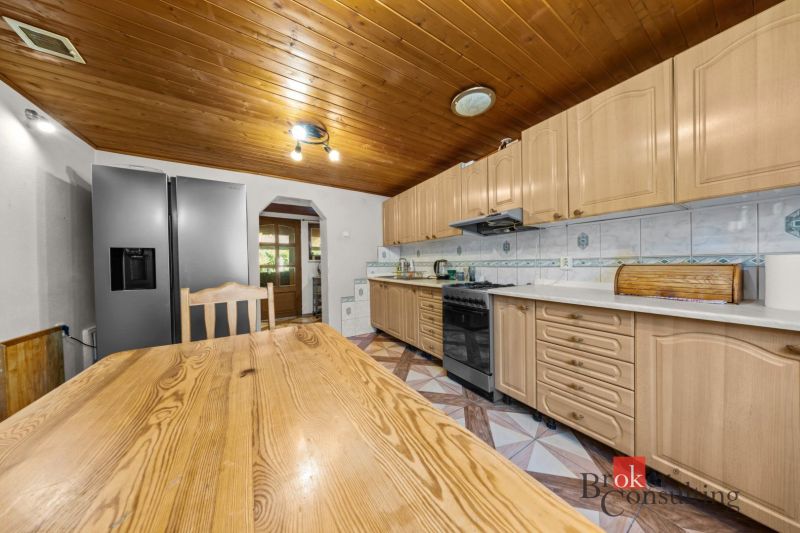 A kitchen in a family house with a light wooden decor on the ceiling and kitchen cabinets.