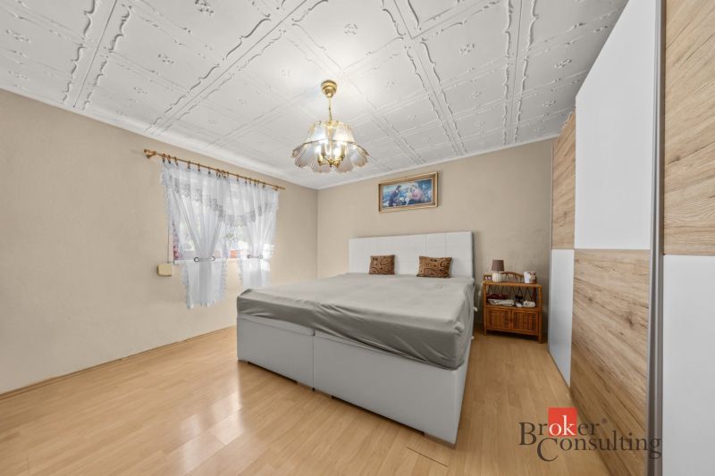 Bedroom in a family house with a wooden decor floor and an elegant chandelier.