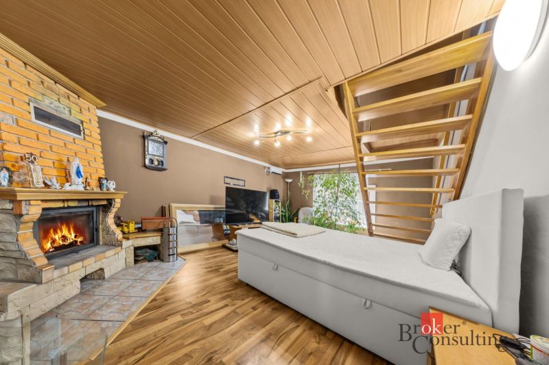 Interior of a family house with a fireplace, staircase, sofa, and wooden decor flooring.