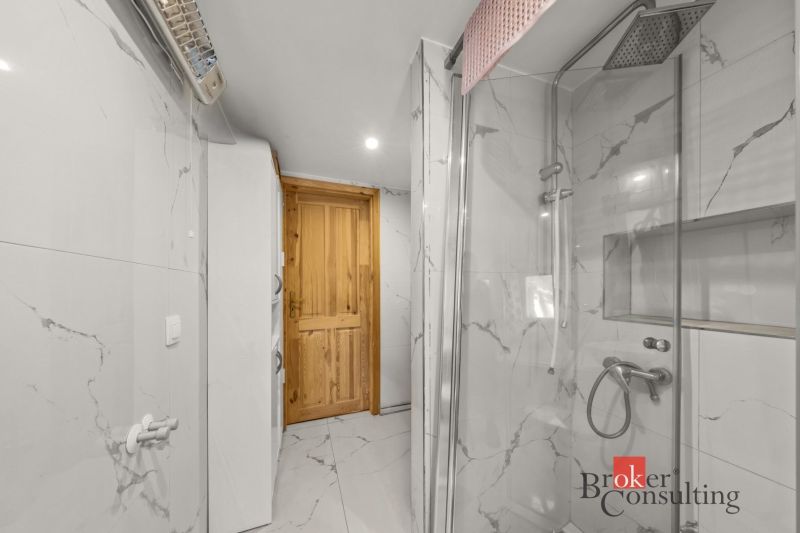 A bathroom with ceramic tiles, a glass shower enclosure, and wooden doors in a family house.