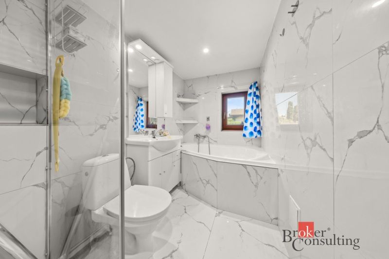 A bathroom with marble tiles and a blue curtain in a family house.