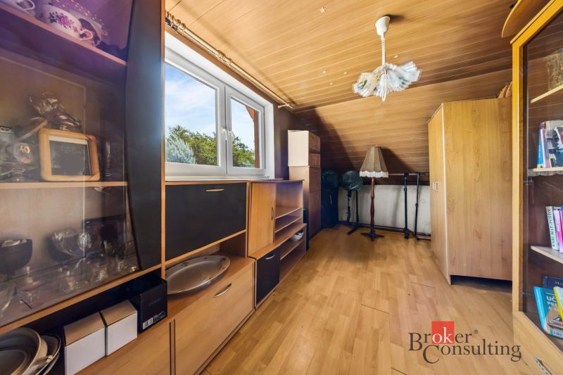 Attic room in a family house with wooden furniture and a view of the garden.