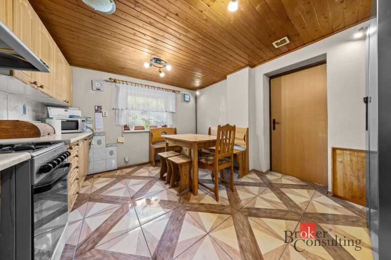 A kitchen in a family house with wooden paneling on the ceiling and a table for four.