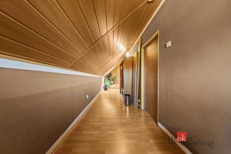 A hallway in a family house with a wooden decor floor and a slanted ceiling.