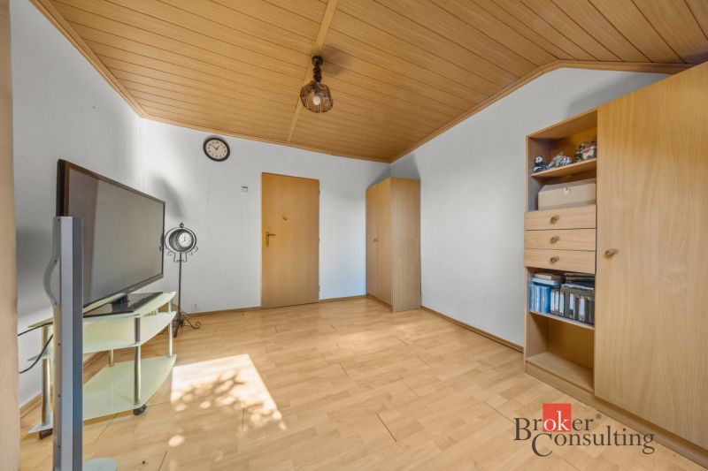 A room in a family house with a wooden decor floor, a television, and furniture.