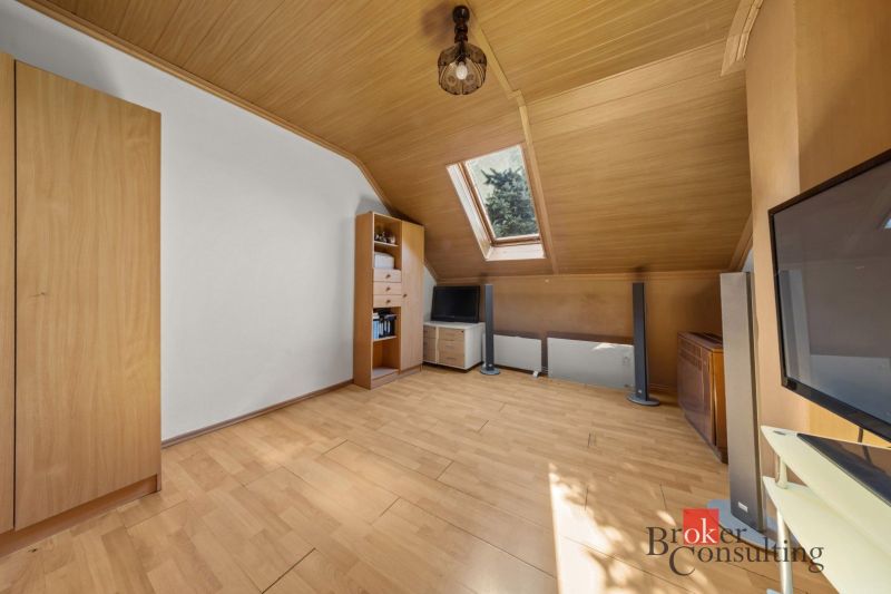 Attic room with wooden decor, skylight, light furniture.