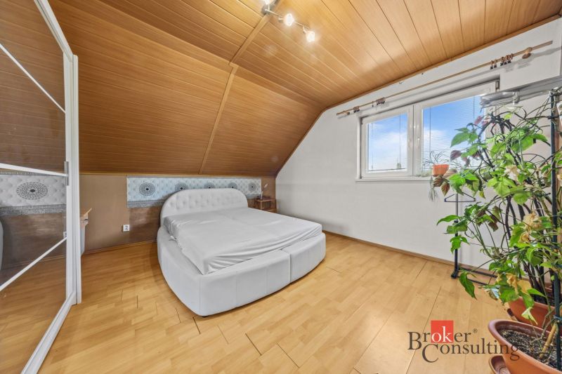 Bedroom in a family house with a bed, decorative wall, and floor with wood decor.