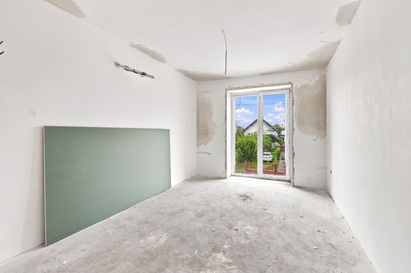 Interior of a family house with an incomplete wall and a view of the garden.