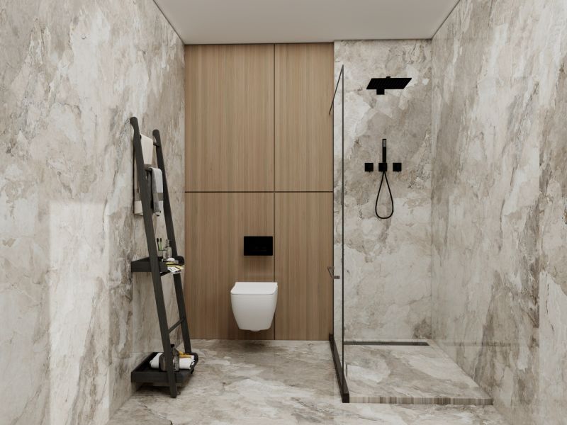 A bathroom in a family house with marble imitation on the walls and a glass shower enclosure.