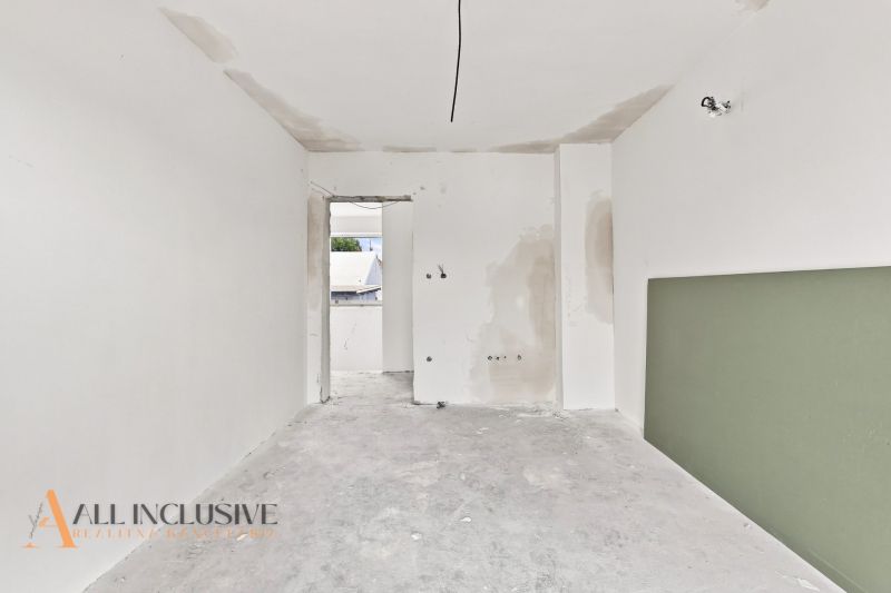 A white room in a family house with two open doors and a green element on the wall.