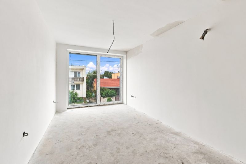 An empty room with a view from the window in a family house, without flooring.