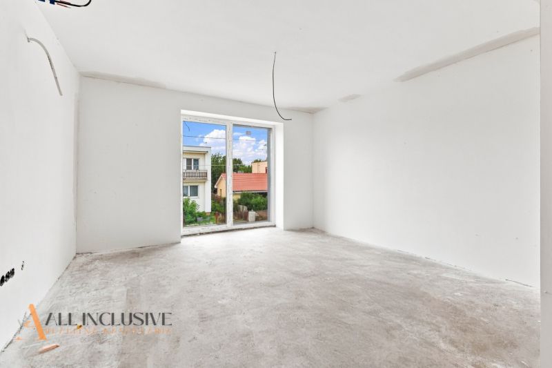 A room in a family house with an unfinished floor, a large window, and a view of the gardens.