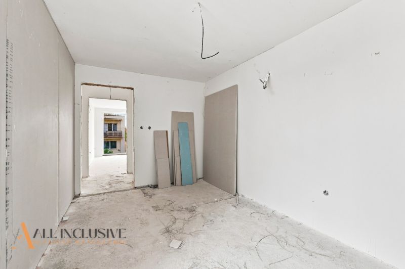 Unfinished room with white walls, electrical wiring, and construction boards in a family house.