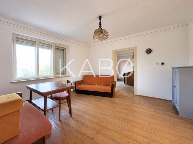 Living room in a family house with a wooden decor floor, furniture, and large windows.