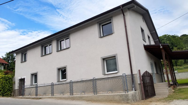 Family house in Ochodnica, a two-story building with a gray facade and an entrance gate.