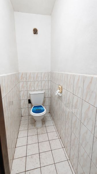 A toilet in a family house with white tiles and a patterned seat.