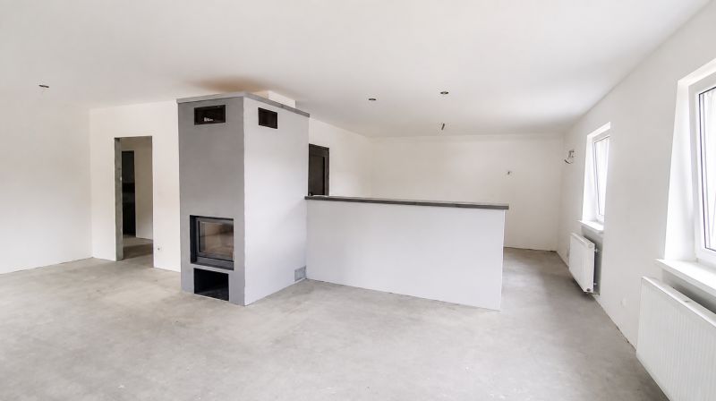White room with a fireplace in a family house, floor with wooden decor.
