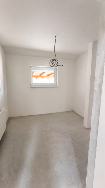 Interior of a family house with white walls and a window next to a light gray floor.