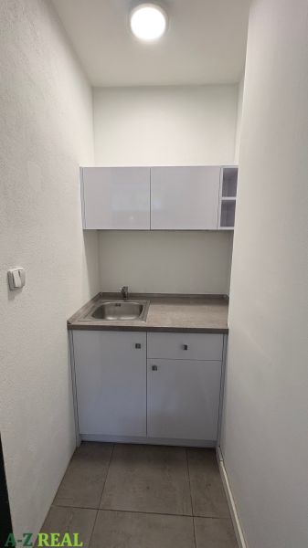 A small kitchenette in commercial premises with a light-colored sink cabinet.