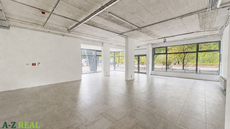 Spacious commercial spaces with large glass walls, flooring, and concrete ceiling.
