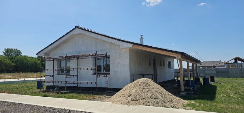 A family house in Bellova Ves under construction with scaffolding and a pile of sand.