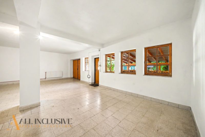 A spacious room with tiled flooring, white walls, and several wooden windows, Land - housing.