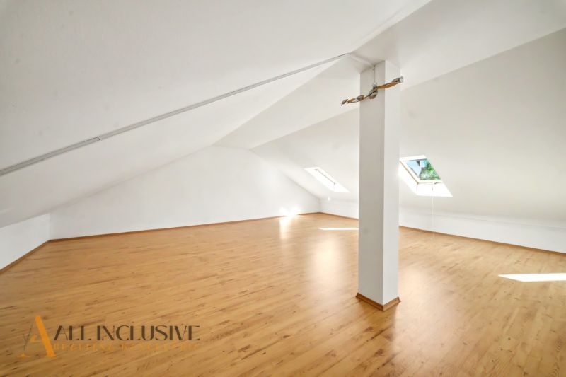Attic space with a wooden decor floor and skylights suitable for living.