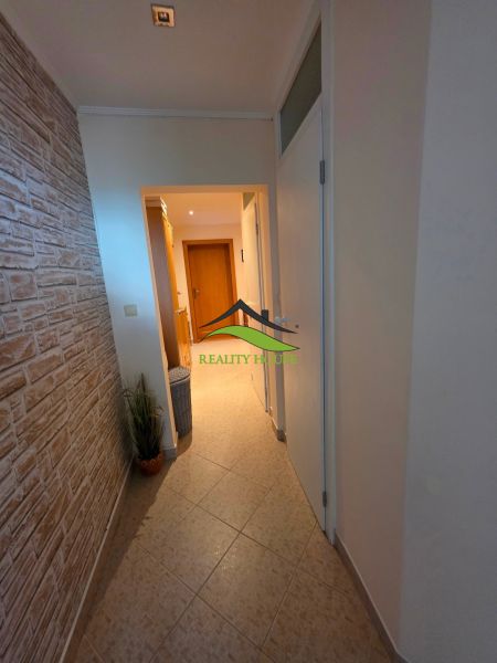 A hallway with stone cladding and tiles in a 3-room apartment.
