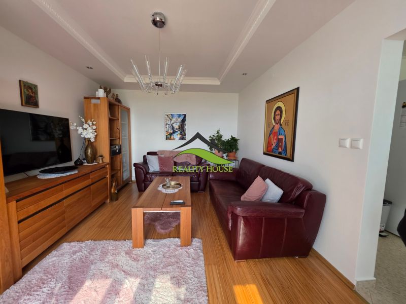 Living room in a 3-room apartment with a wooden decor floor, leather sofa, and decorations.