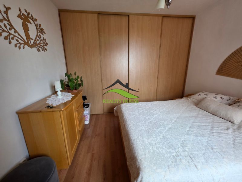 A bedroom in a three-room apartment with a double bed, a wardrobe, and a floor with a wooden decor.