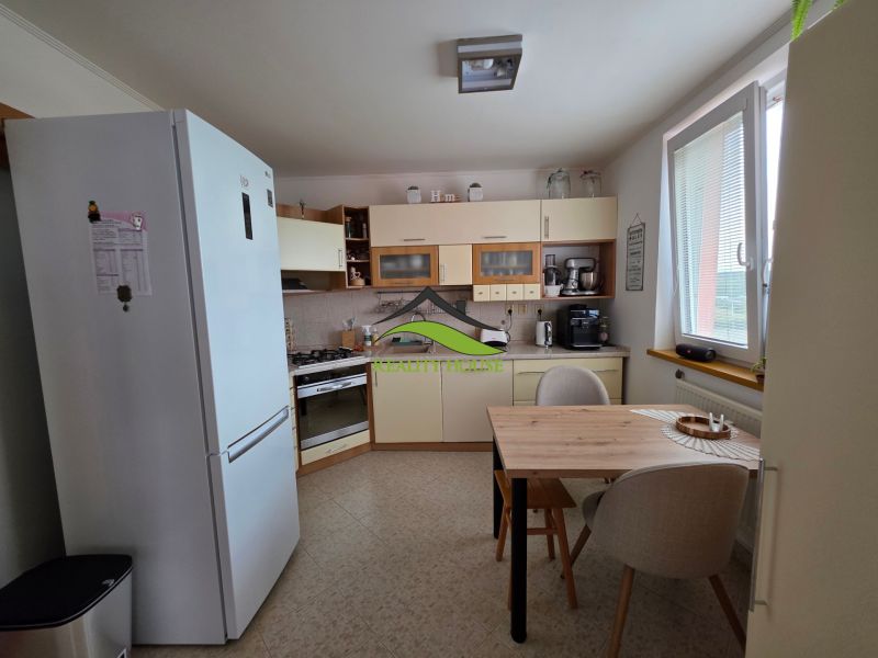A kitchen in a 3-room apartment with a dining table and appliances, floor with a wooden decor.